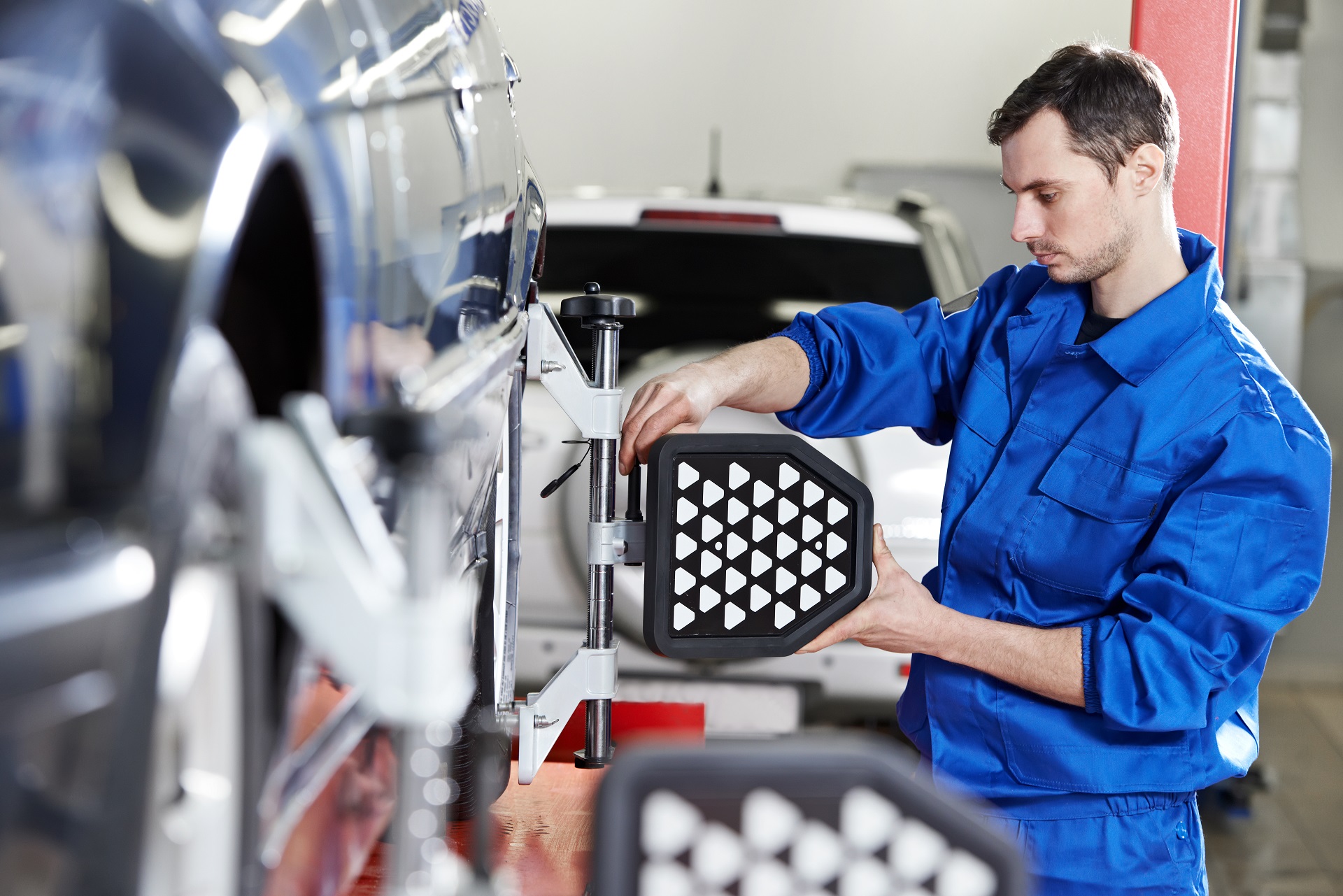 auto mechanic at wheel alignment work with sensor